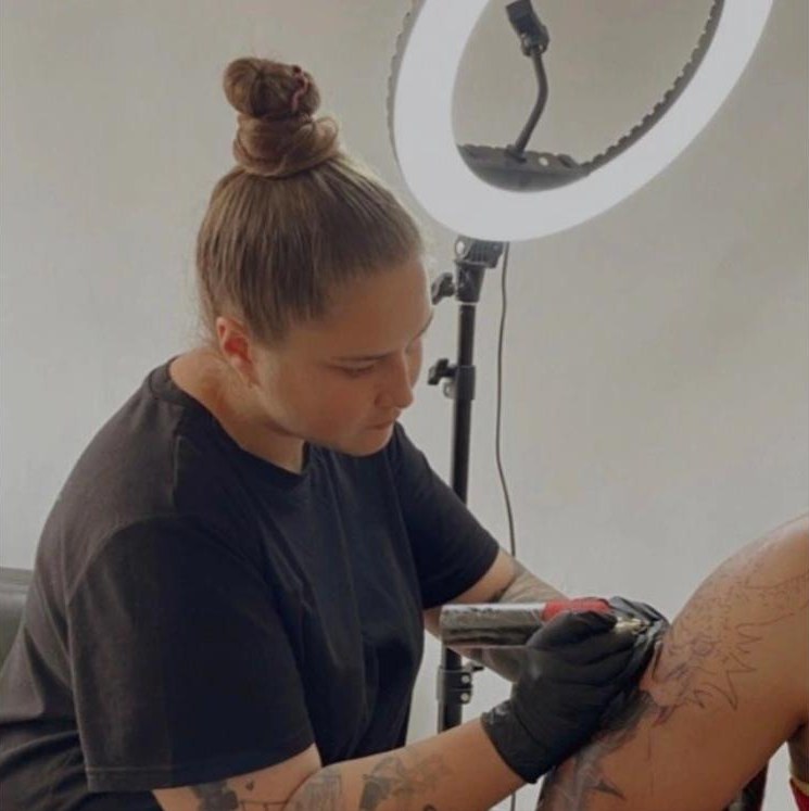 Daria tattooing under a ring light